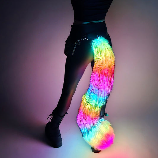 A person wearing a multicolored faux fur tail with LED lights attached to their waist.