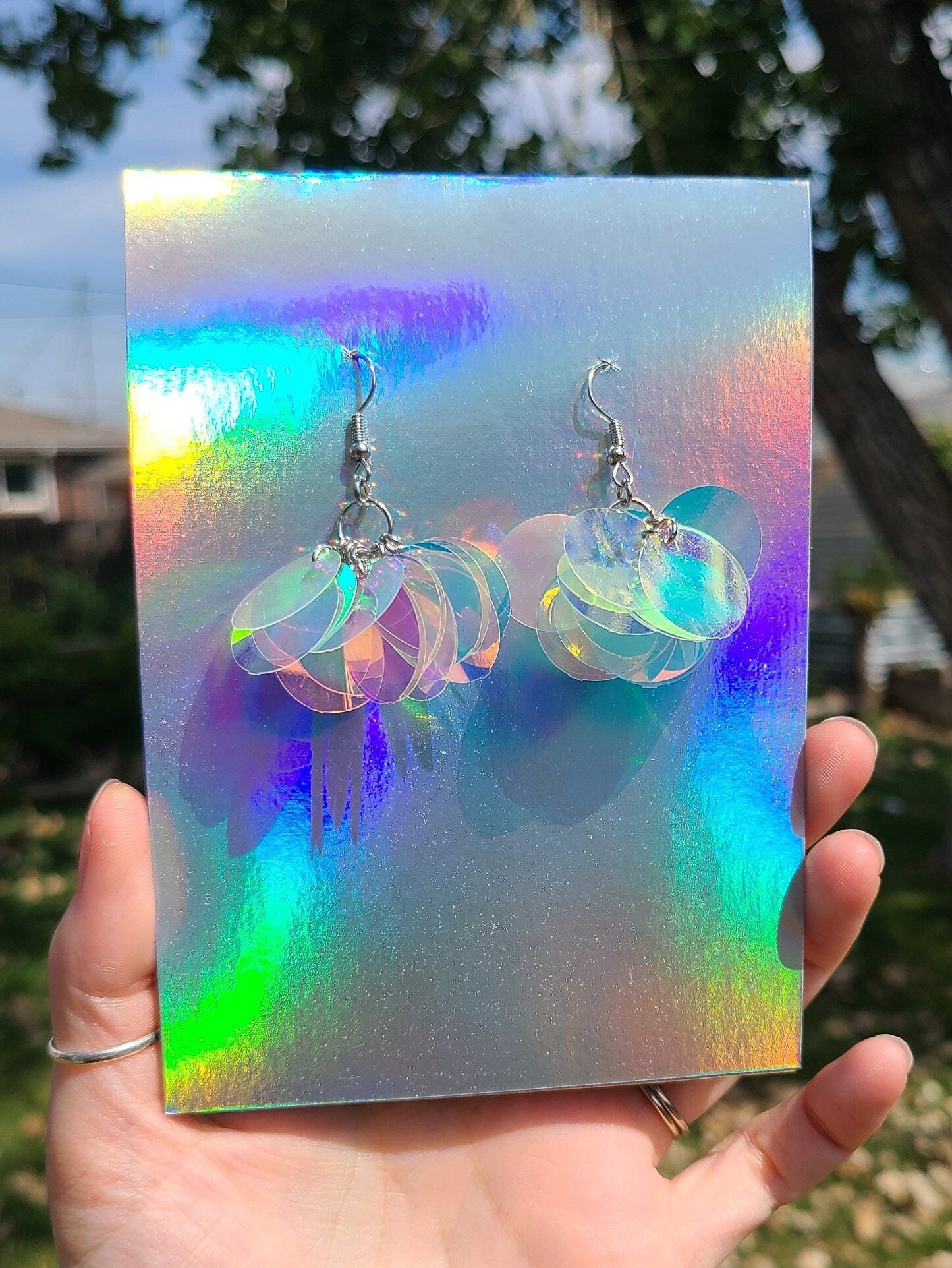 Hand holding iridescent sequin cluster earrings.