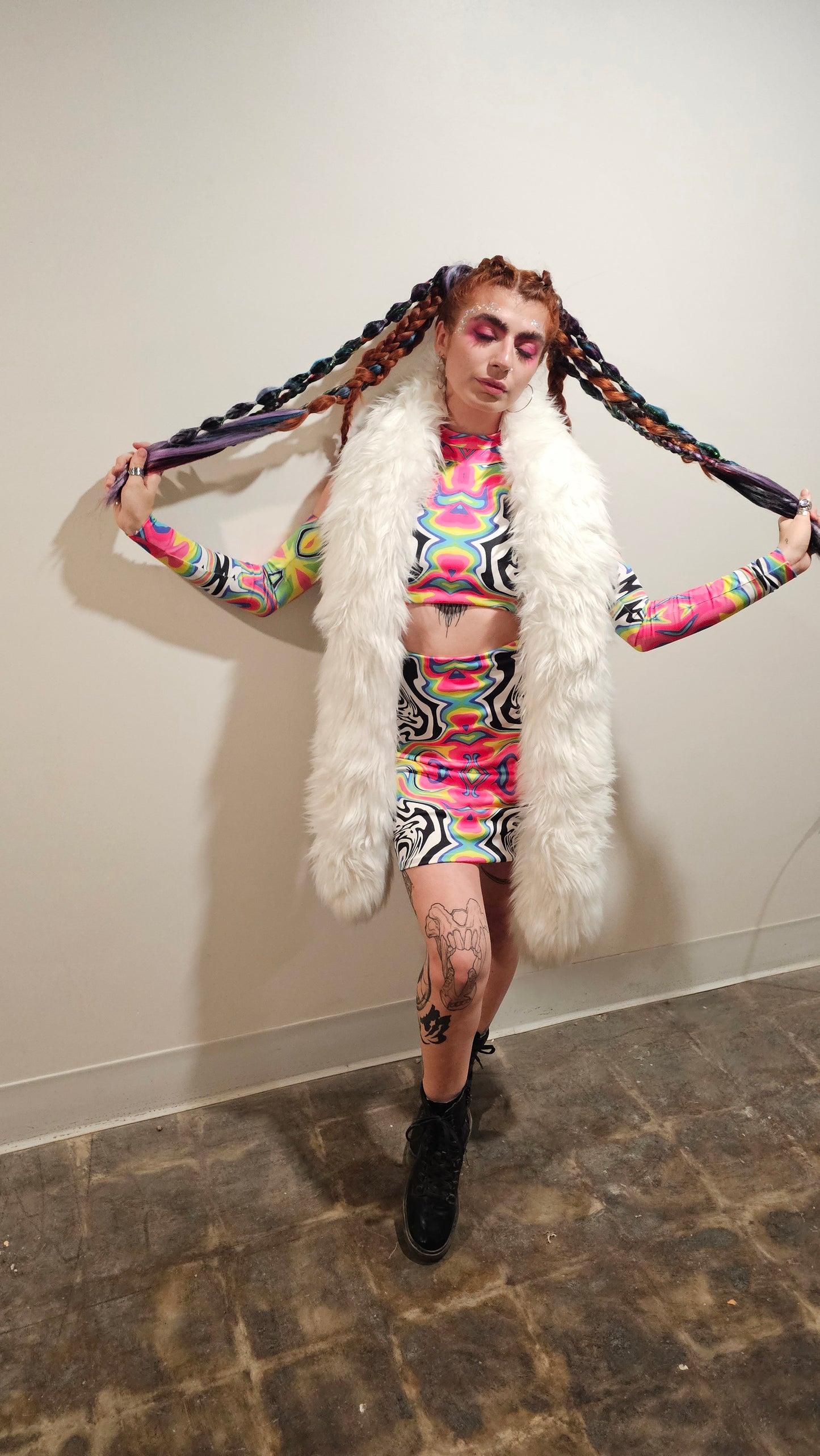 Person in colorful outfit with fur boa on a plain background