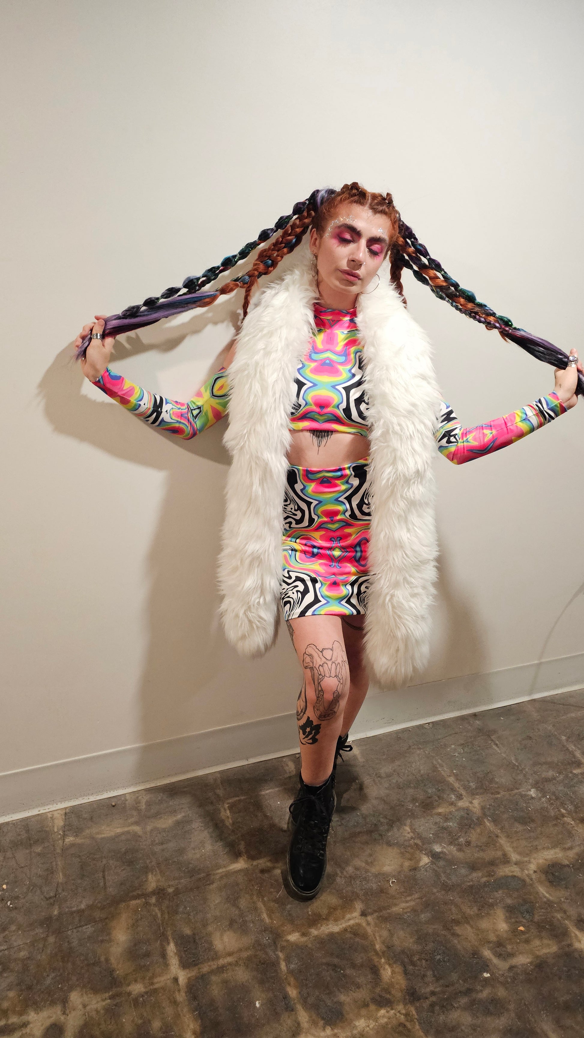 Person in colorful outfit with fur boa on a plain background