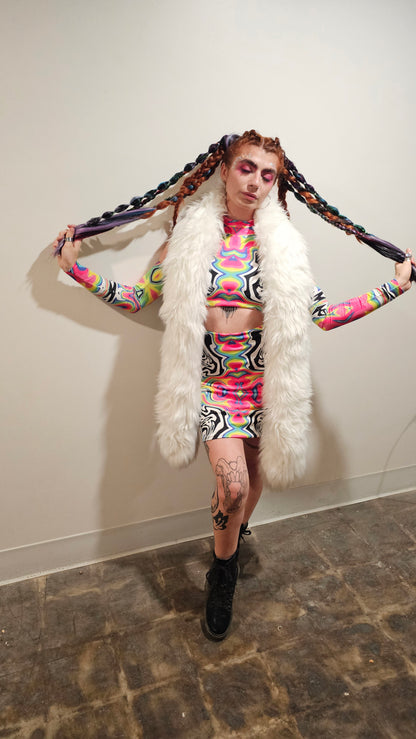 Person in colorful outfit with fur boa on a plain background