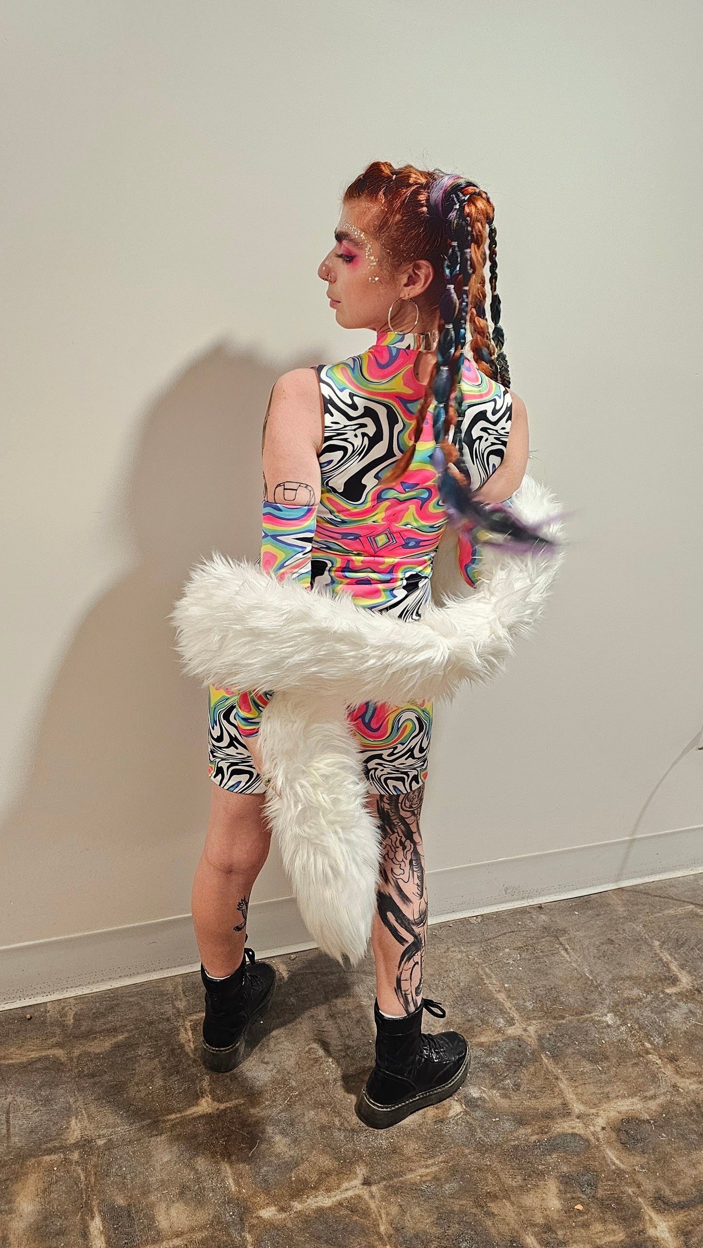 Person wearing a colorful outfit with a fur boa on a stone floor.