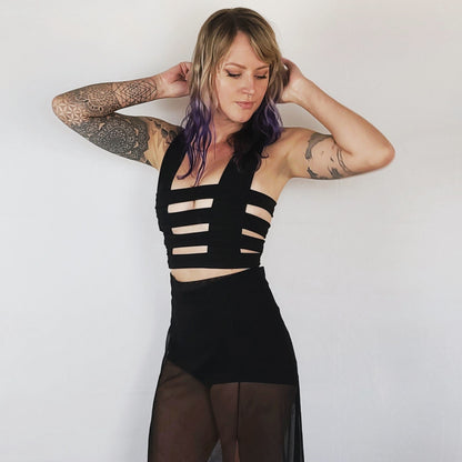 Woman wearing cage bralette, a black bra top with horizontal straps.