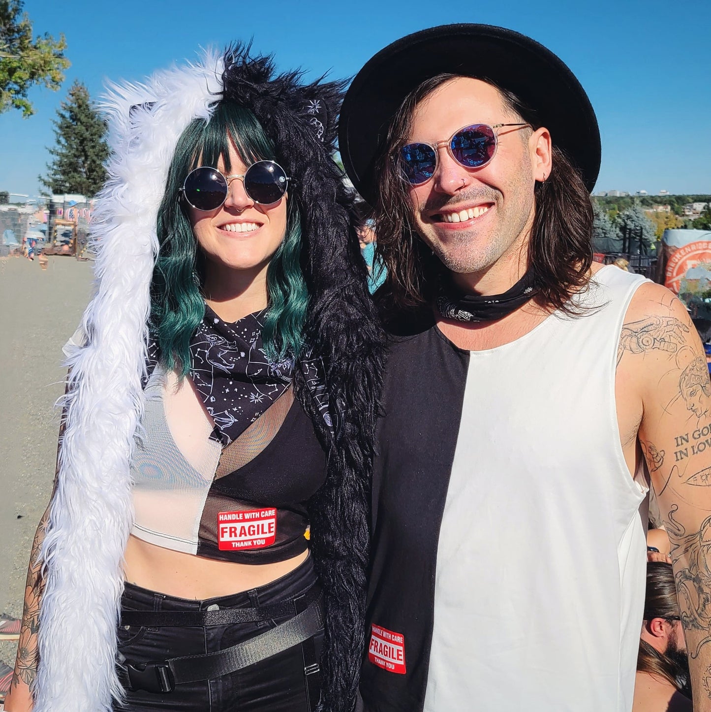 Couple wearing black and white festival outfits, featuring custom black and white faux fur hood.