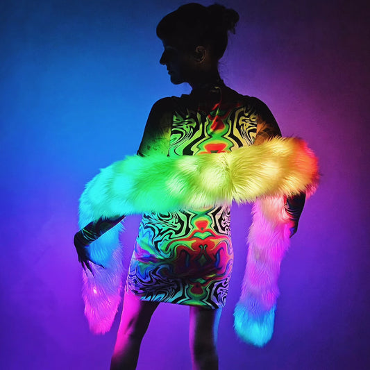 Person wearing a colorful dress with glowing fur accessories against a vibrant background