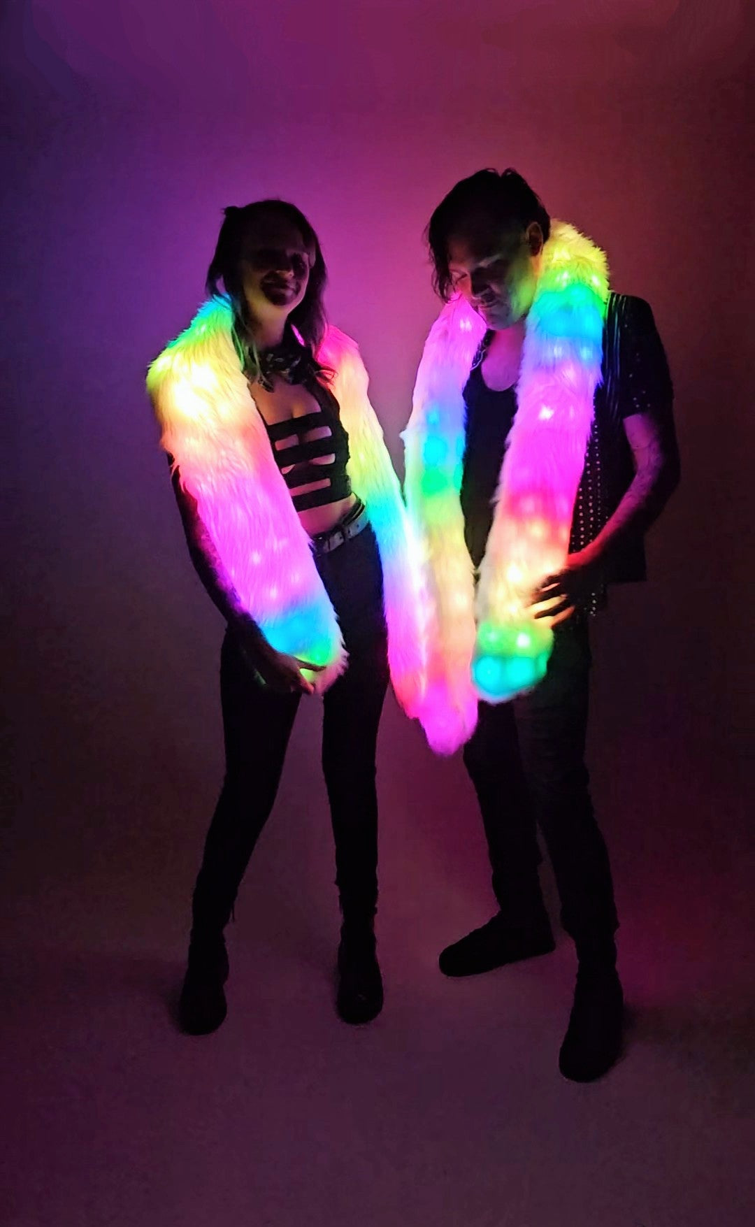 Two people wearing LED scarves against a dark background