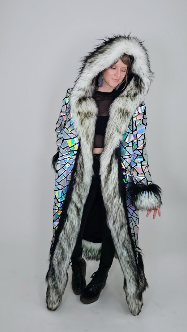 Person wearing a long, colorful coat with fur trim on a gray background