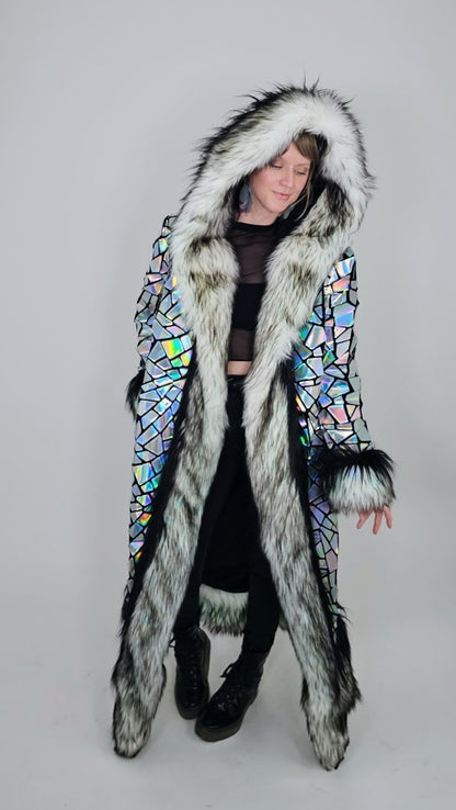 Person wearing a long, colorful coat with fur trim on a gray background