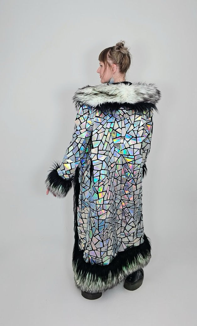 Person wearing a hologrpahic mosaic-patterned coat with fur trim on a plain background