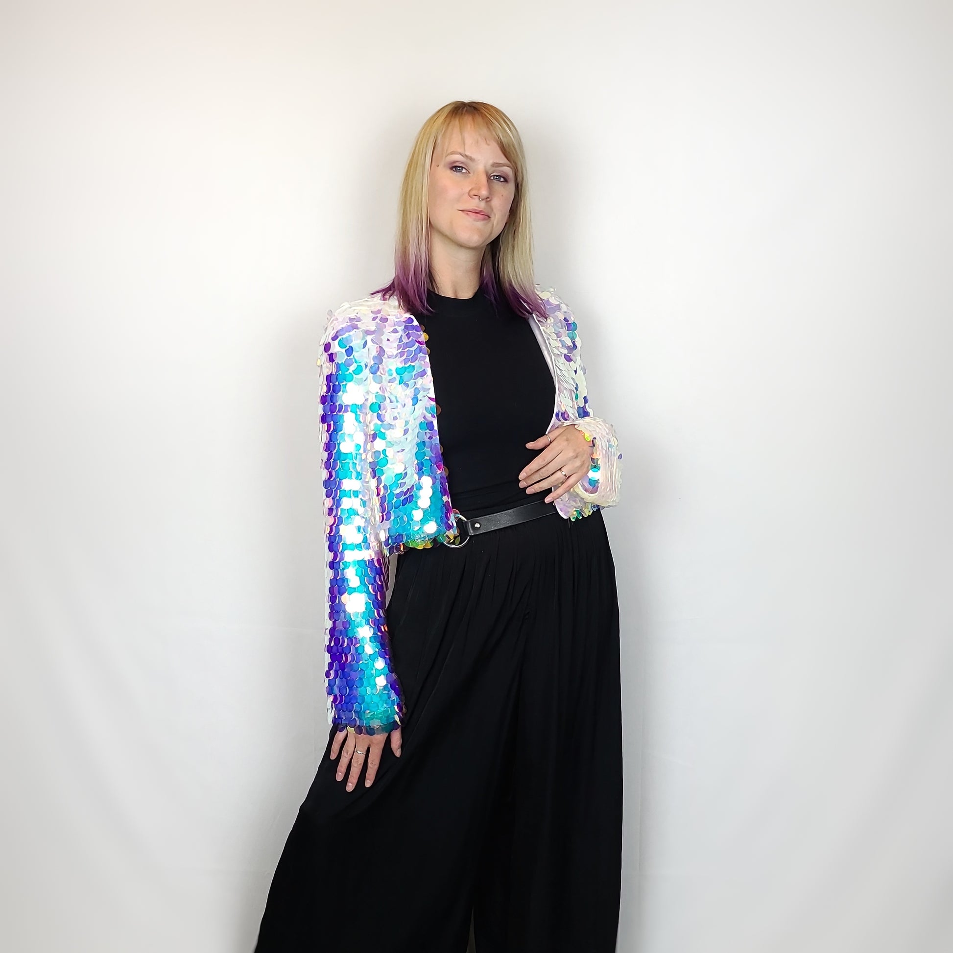 Woman wearing a cropped sequin jacket with blue iridescent sequins and white satin lining