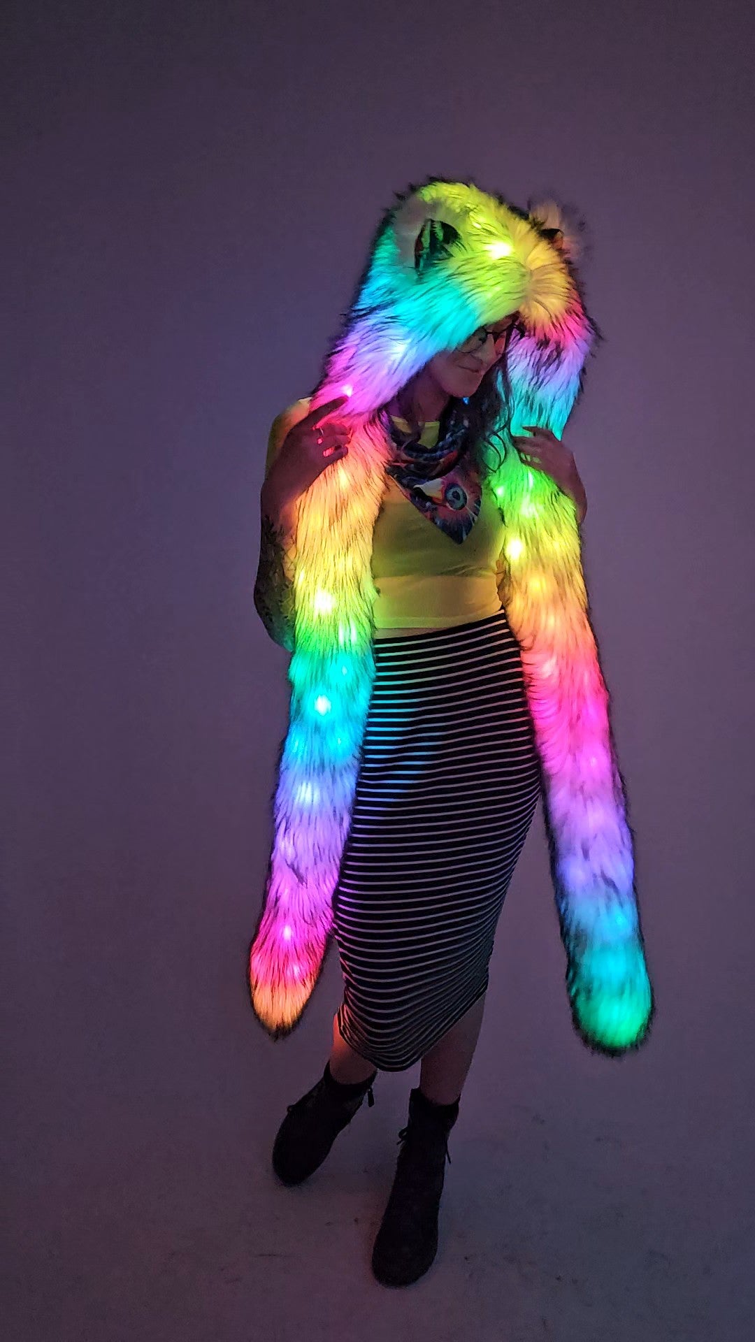 Person wearing a colorful, illuminated faux fur hood against a plain background