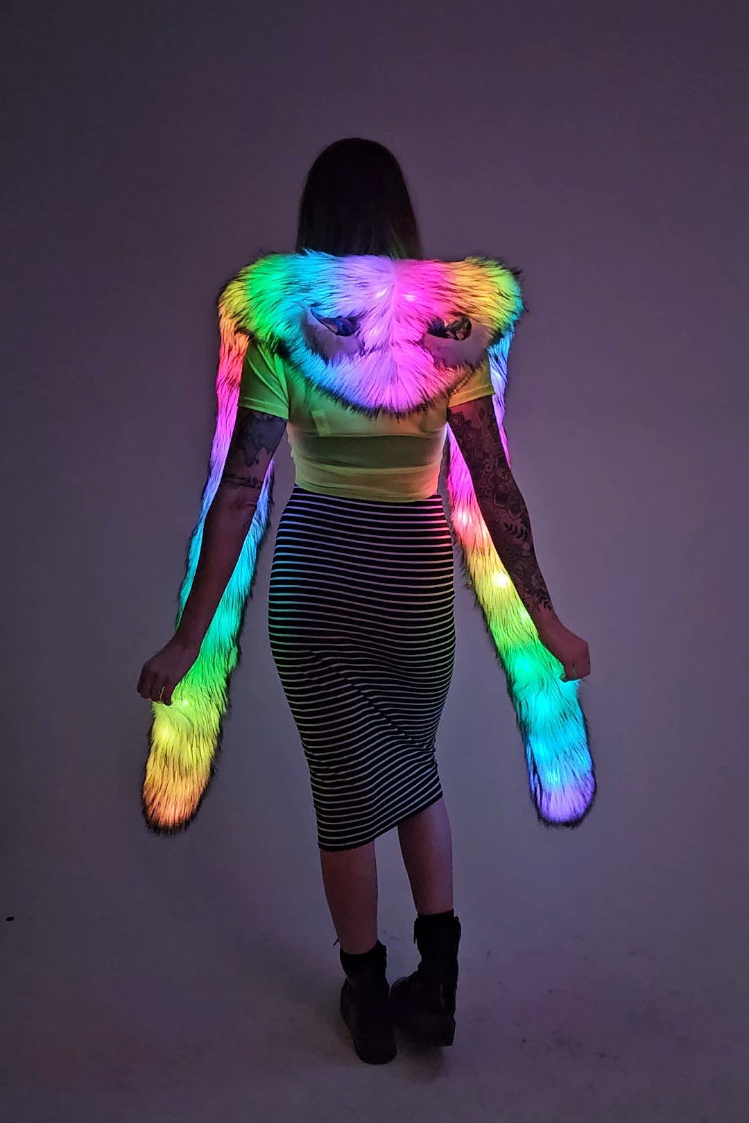 Person wearing a colorful, glowing hood against a dark background