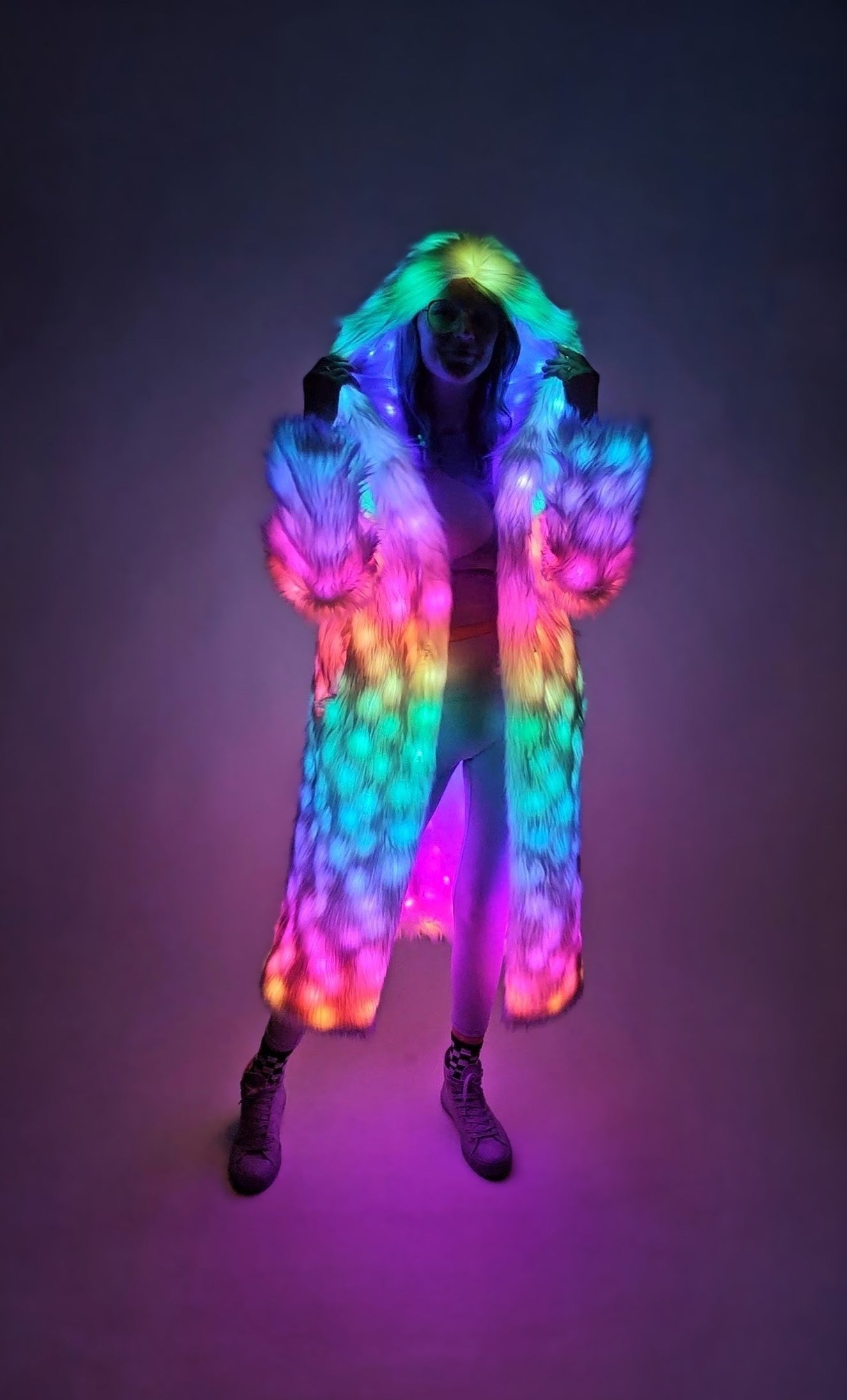 Person wearing a colorful, illuminated coat against a dark background
