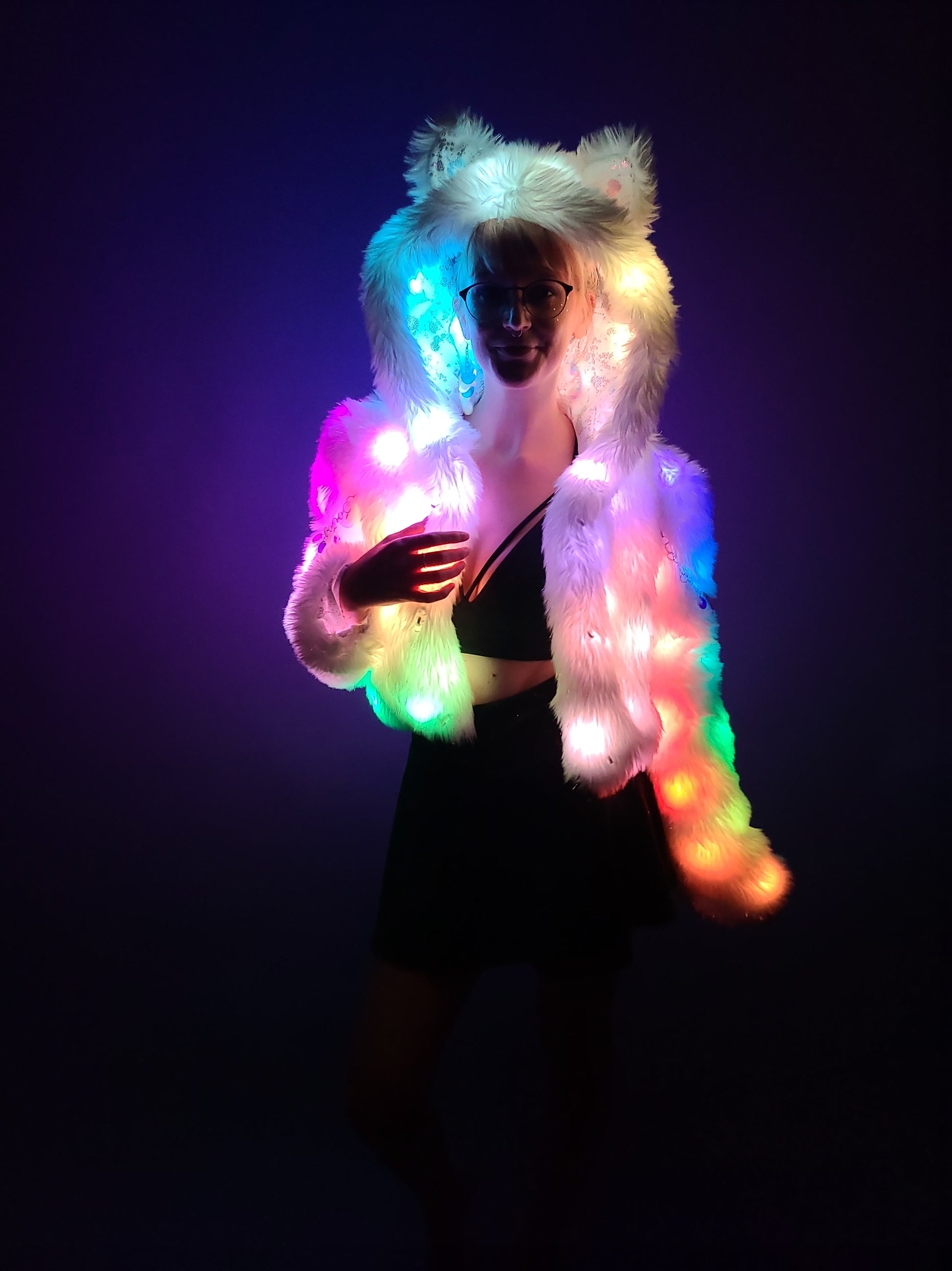 Woman wearing a cropped faux fur coat illuminated by rainbow color leds.