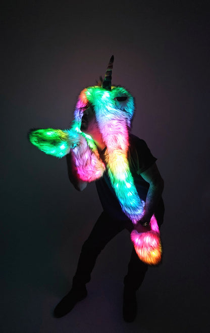 Person wearing a colorful led unicorn hood with glowing elements on a dark background