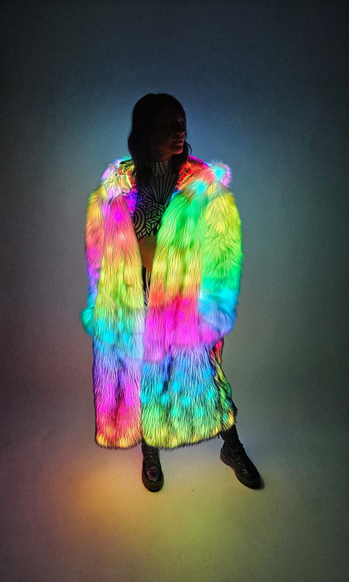 Person wearing a colorful, illuminated fur coat against a dark background