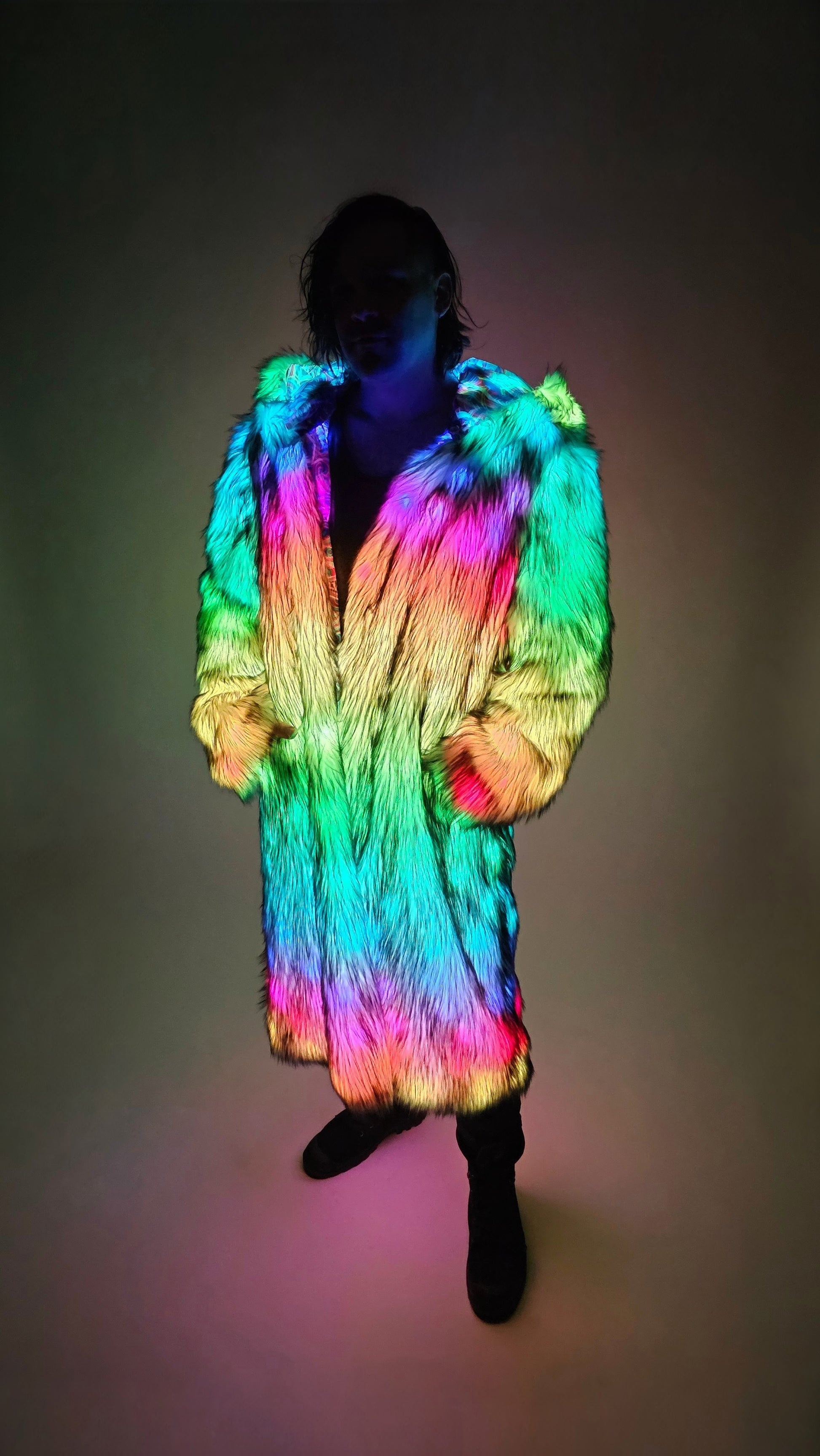 Person wearing a colorful, illuminated fur coat against a dark background