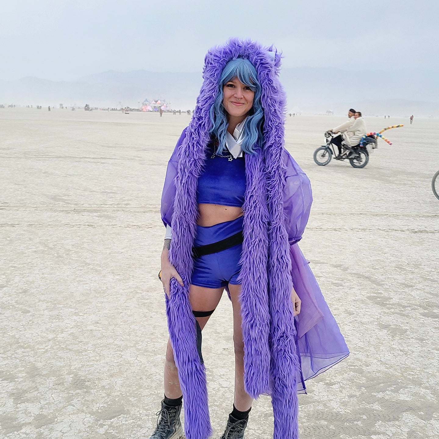 Woman at burning man wearing a periwinkle faux fur hood