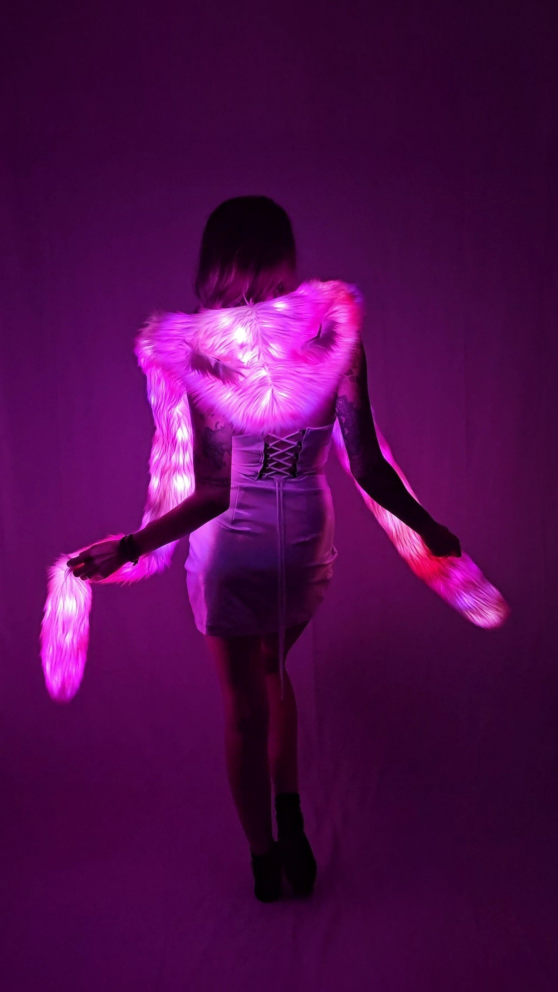 Person wearing a glowing pink led hood against a purple background