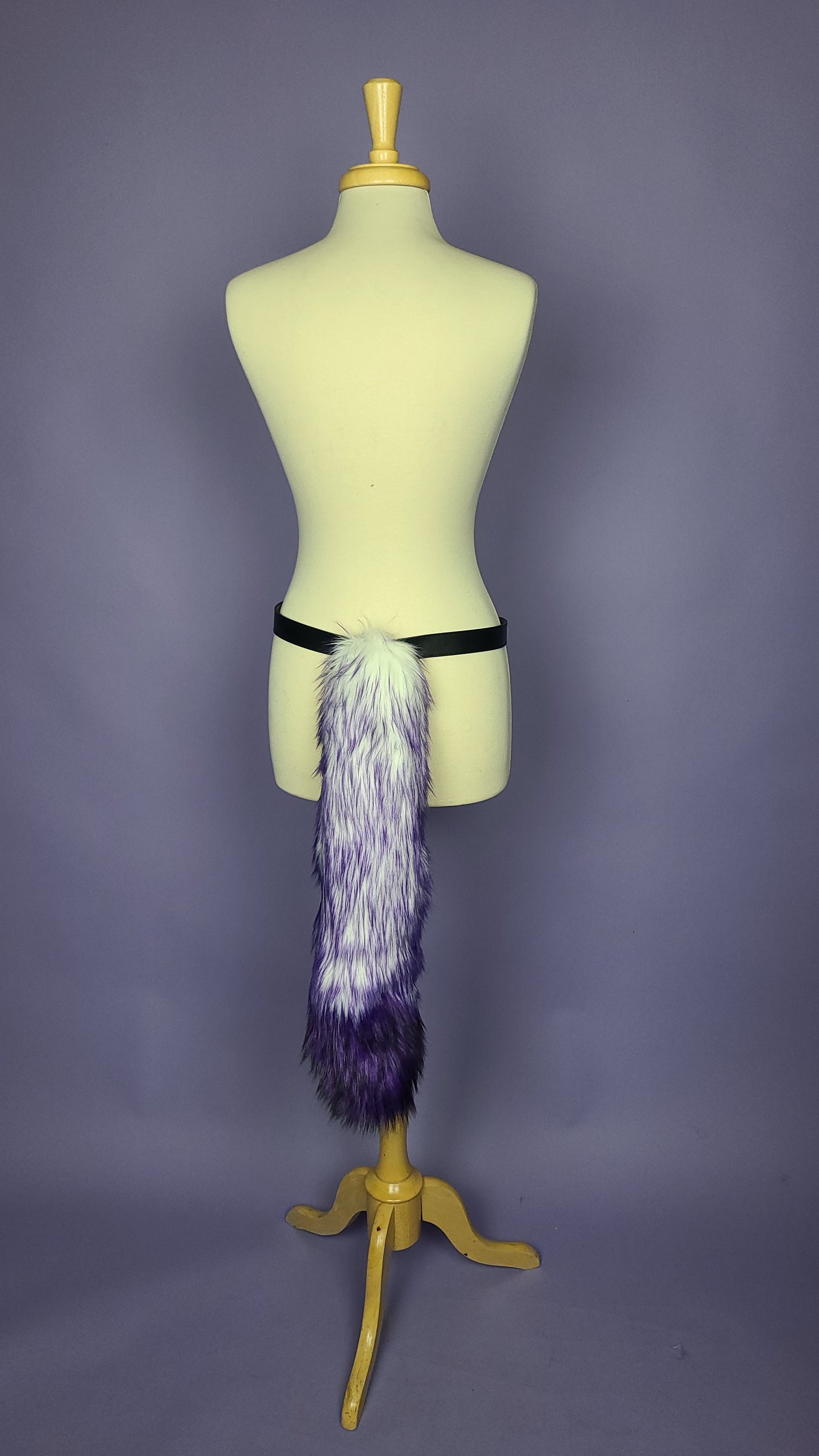 Purple faux fur costume tail on a mannequin.