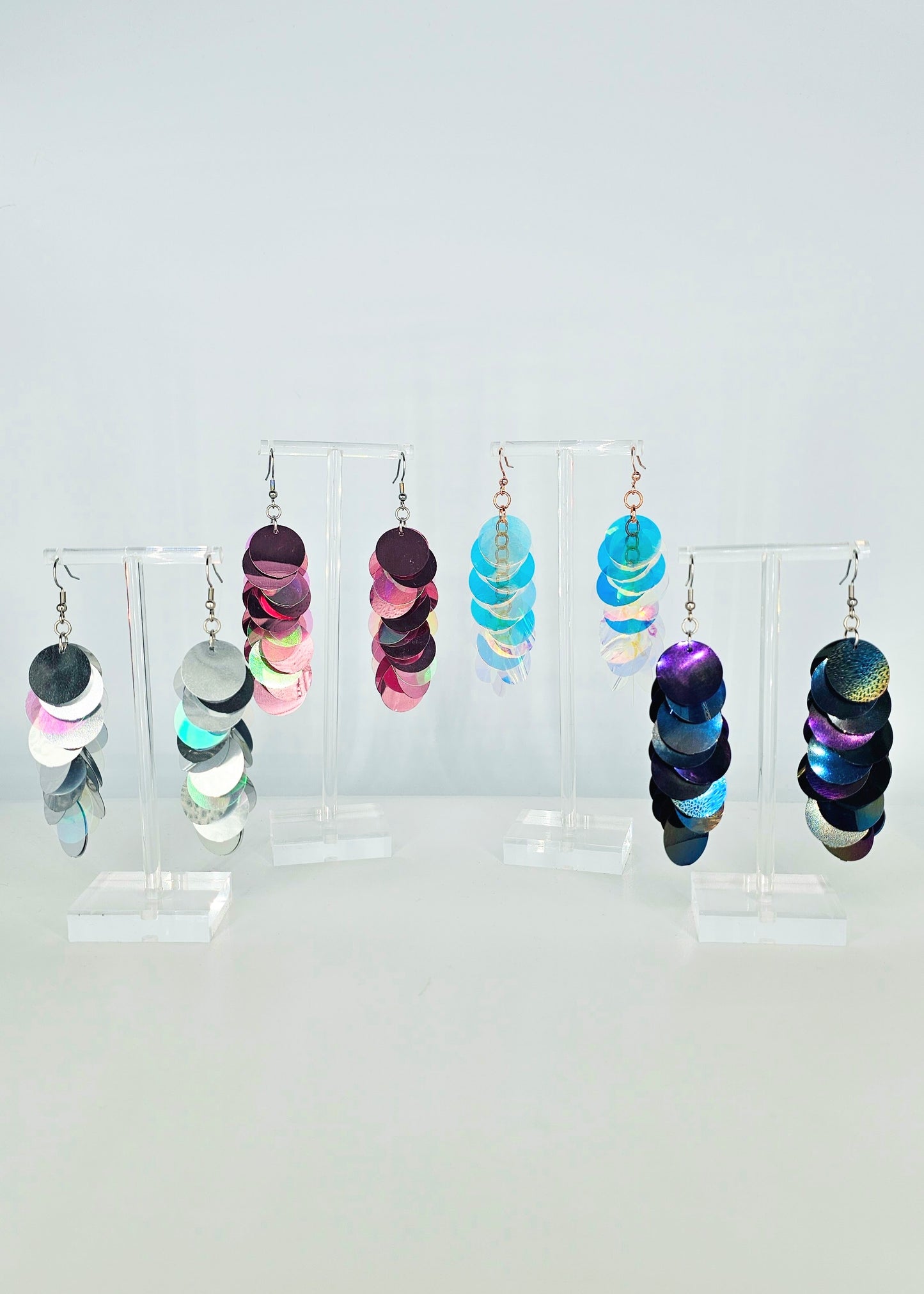 Colorful earrings on a clear stand against a white background
