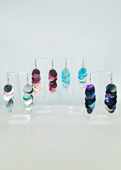 Colorful earrings on a clear stand against a white background