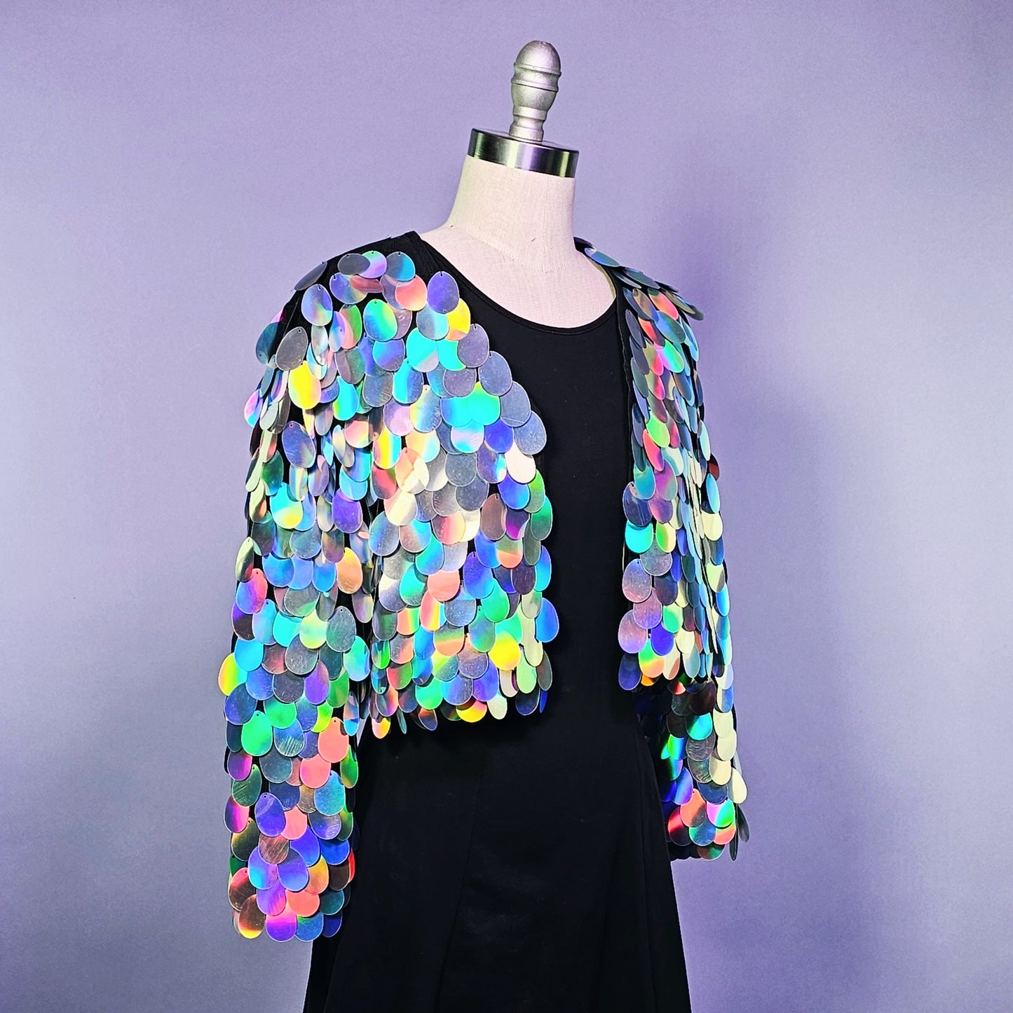 Mannequin wearing a cropped sequin jacket made with iridescent silver sequins and black satin lining