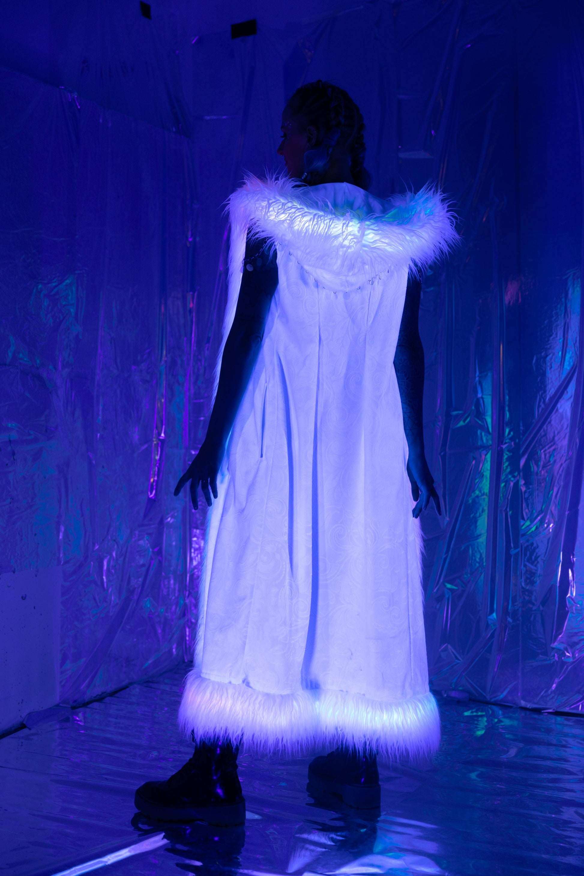 Long white velvet duster vest with white faux fur trim viewed with blacklight.