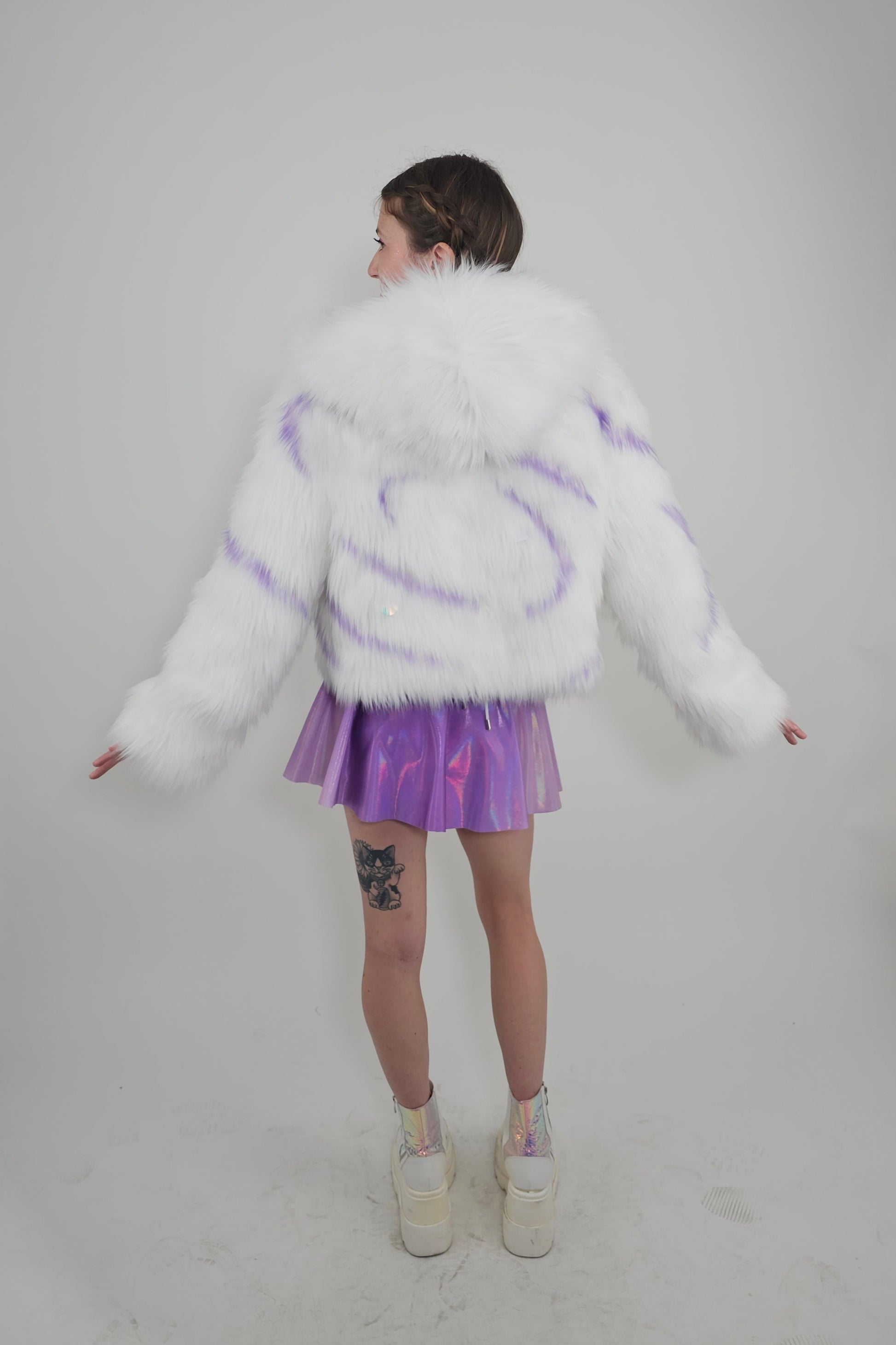 Model wearing white faux fur coat and lavender outfit