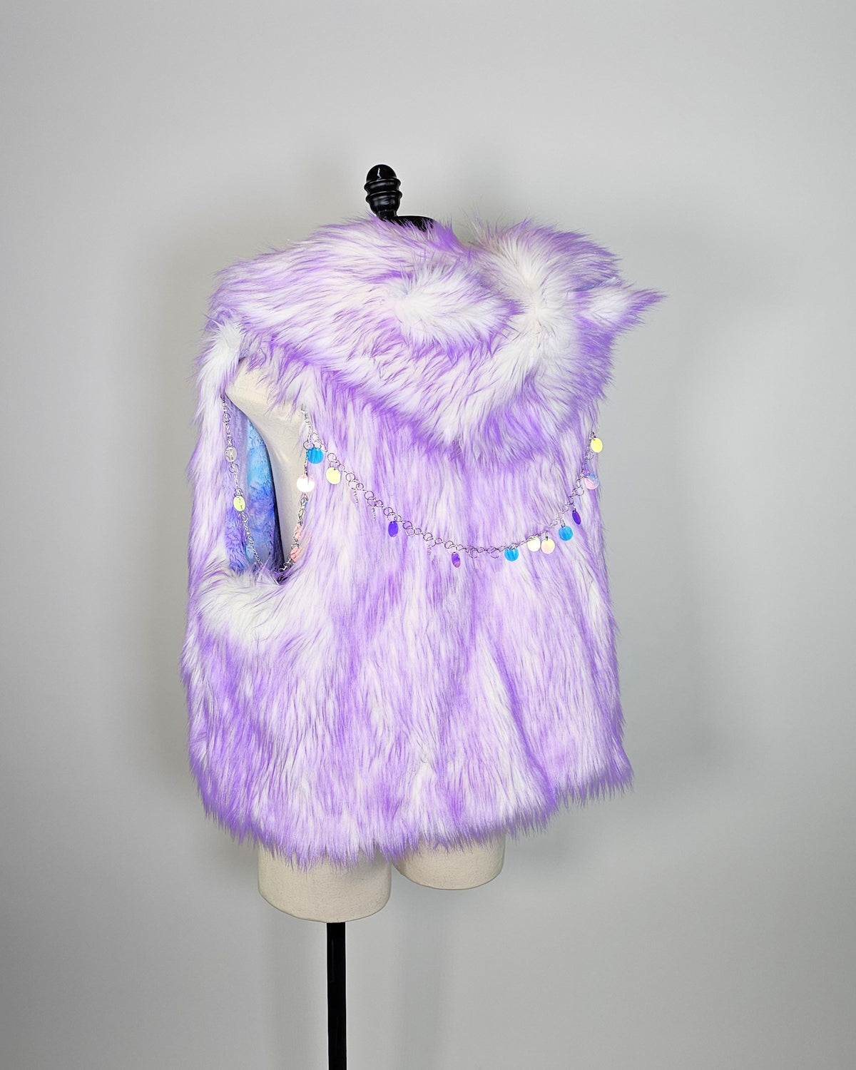 A lavender and white faux fur vest with a decorative beaded chain across the chest, displayed on a mannequin torso against a light gray background.